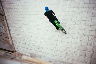 一位戴着蓝色帽子的年轻白人男性自行车手在街上停了下来