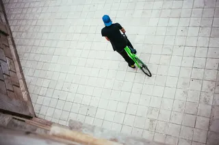 一位戴着蓝色帽子的年轻白人男性自行车手在街上停了下来