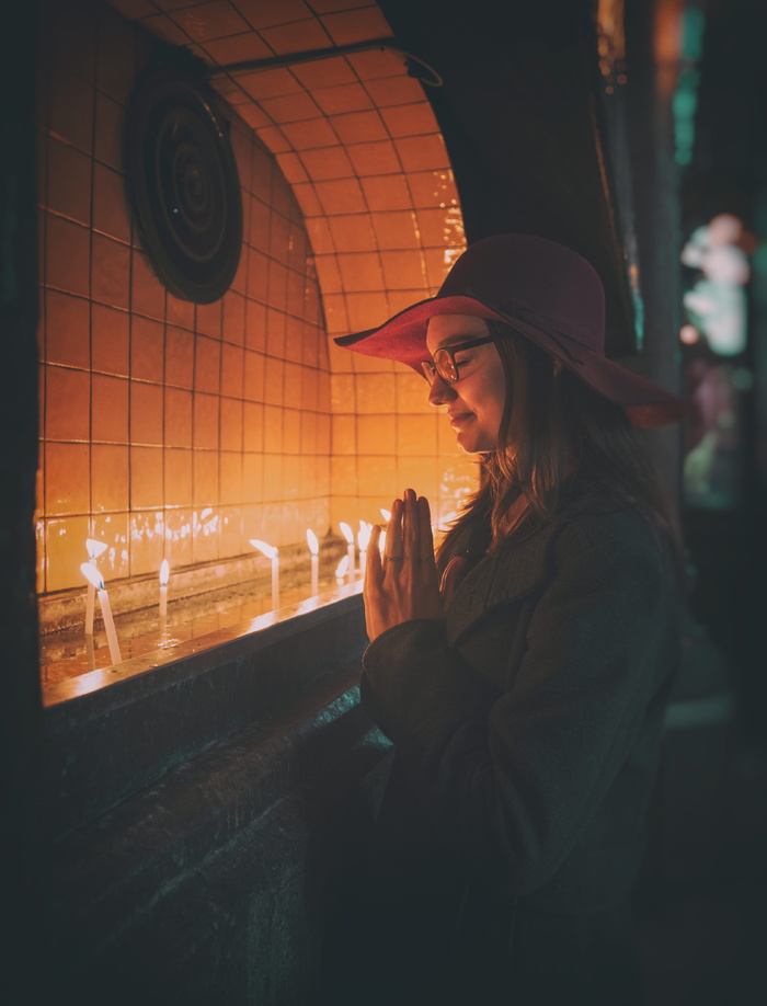 在点燃的蜡烛前祈祷的女人