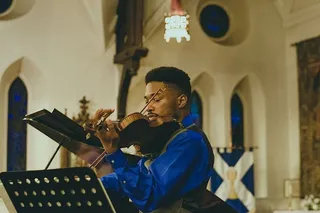 建筑物内拉小提琴的男子