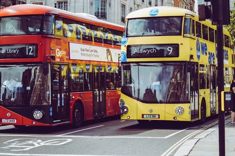 灰色混凝土道路上的两辆黄色和红色双层巴士