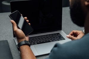 在MacBook Pro附近用左手拿着iPhone的人