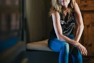 一位身穿朋克服的金发女郎双手放在膝盖上坐着