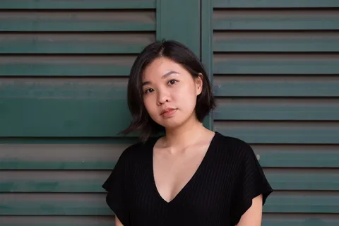 身穿黑色低垂领口连衣裙的女子站在绿色墙面前 身穿黑色低垂领口连衣裙的女子站在绿色墙面前