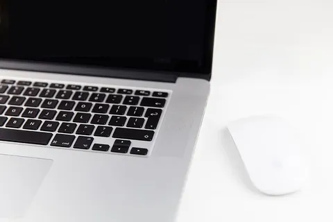 苹果Macbook Pro笔记本电脑和魔法鼠标位于极简主义的纯白色木桌上 苹果Macbook Pro笔记本电脑和魔法鼠标位于极简主义的纯白色木桌上