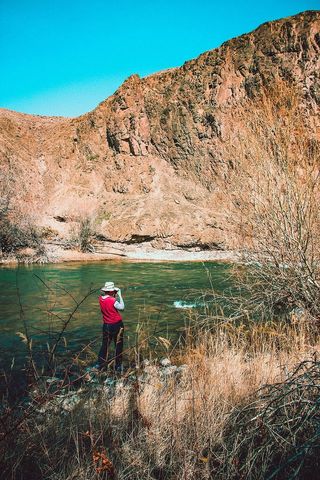 穿着红色和灰色长袖衬衫的人站在水体附近