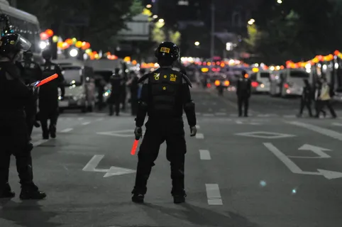 夜间站在灰色沥青路面上的警察 夜间站在灰色沥青路面上的警察