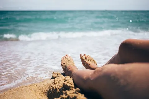 沙滩上的沙脚,背景是波浪和地平线 沙滩上的沙脚,背景是波浪和地平线