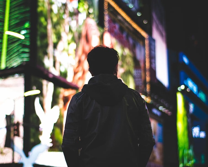 夜间穿着皮夹克的人在LED标志背景下的选择性聚焦摄影