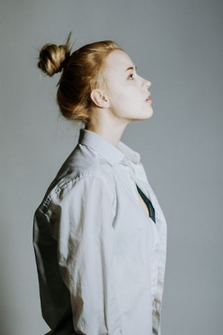 身着灰色连衣裙衬衫的女子抬头的侧视照片