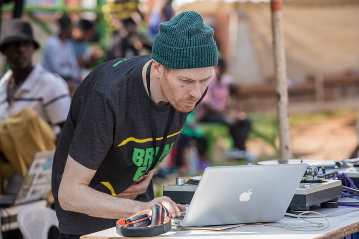 在黑色和橙色耳机旁使用MacBook的男子