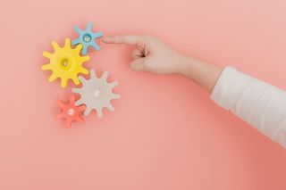 用手指转动桃色墙上的彩色玩具齿轮