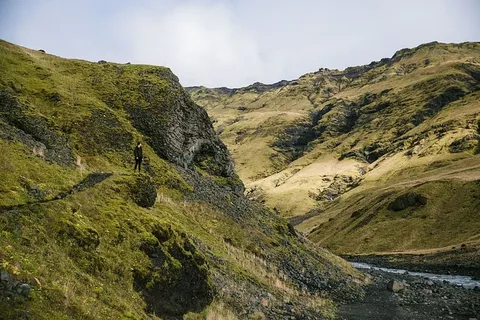 一名年轻的高加索徒步旅行者在冰川流附近的青山上行走 一名年轻的高加索徒步旅行者在冰川流附近的青山上行走
