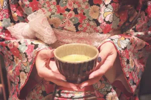 身穿红、白、青三色碎花连衣裙、手持白色陶瓷碗的女子