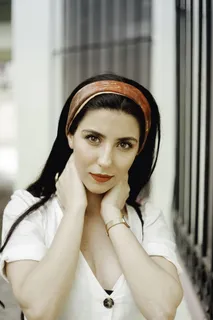 白天站在白色混凝土墙附近的女人，双手放在脖子上