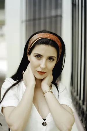 白天站在白色混凝土墙附近的女人，双手放在脖子上