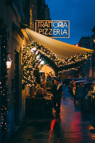 一名男子站在Trattoria Pizzeria店外