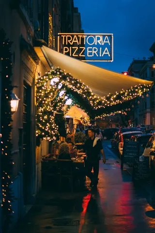 一名男子站在Trattoria Pizzeria店外