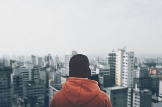 穿着橙色连帽衫盯着建筑物的人