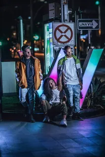 一名女子坐在路边石上，两名男子站在路标前