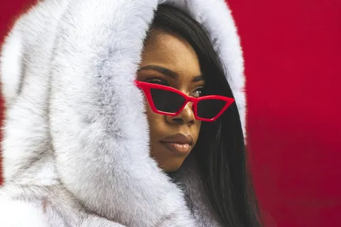 身穿白色毛皮大衣、戴墨镜的女子