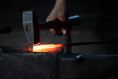 人用锤子敲击热铁棒 人用锤子敲击热铁棒