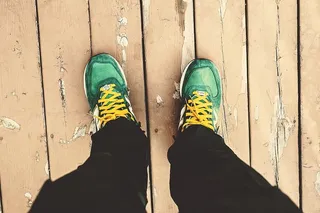 一个男人低头看着他的绿色运动鞋