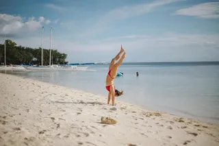 在海岸线上做头部站立的女人
