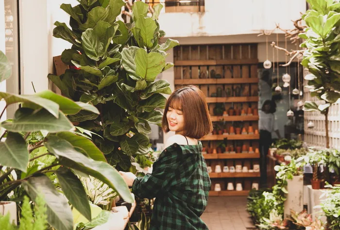 一位微笑的女子站在灌木丛旁的照片