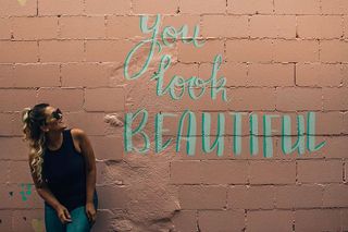 女人站在米色的水泥砖上，你看起来很漂亮