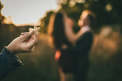 拿着蒲公英的人的选择性聚焦摄影 拿着蒲公英的人的选择性聚焦摄影