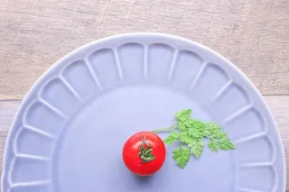 绿色蔬菜和红色食物放在灰色木质表面的蓝色陶瓷板上