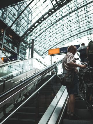 站在自动扶梯上手持自行车的男子