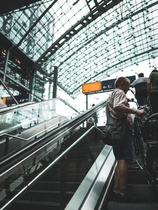 站在自动扶梯上手持自行车的男子