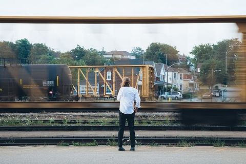 一个留着长发的白人青年站在路过的火车旁