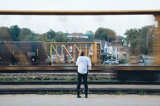 一个留着长发的白人青年站在路过的火车旁