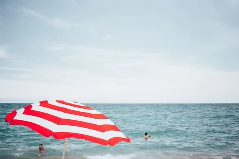 一把沙滩伞，背景是游泳的人