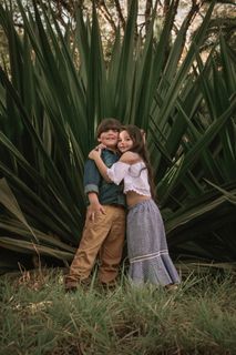 男孩和女孩站在绿叶植物附近