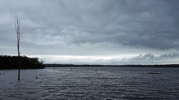 在暴风雨的天空下，帆船停泊在马纳斯坎水库的水面上。