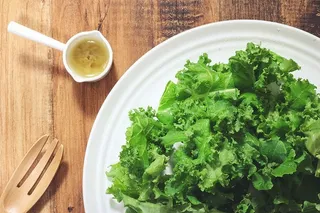 白色陶瓷盘子上的沙拉，配酱汁和木叉