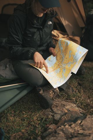 穿着 The North Face 夹克的人拿着地图坐在沙发上