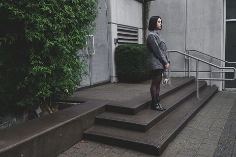 站在绿色植物附近穿着运动夹克的女人