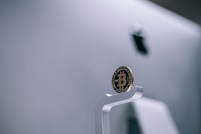 放置在iMac上的黄金物理比特币。物理加密货币硬币。