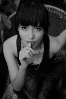 女性咬右手拇指时坐着的灰度照片