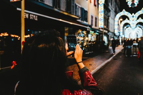 一名女子在夜间拍摄带有弦灯的拱形街道花色