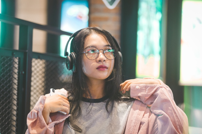 举着智能手机戴着耳机的女性的选择性聚焦摄影