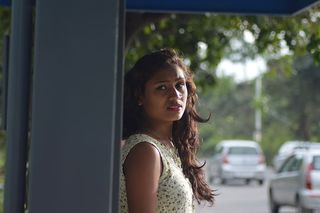 身穿白色上衣的女子倚在灰色钢棚上的照片