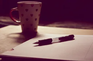 白色陶瓷杯旁白色打印纸上的黑色笔