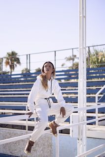 白天穿着白色套头衫连帽衫和裤子坐在扶手上的女士