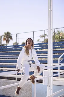 白天穿着白色套头衫连帽衫和裤子坐在扶手上的女士